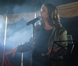 Live singer performing in atmospheric lighting at Meadow Tree Marquee